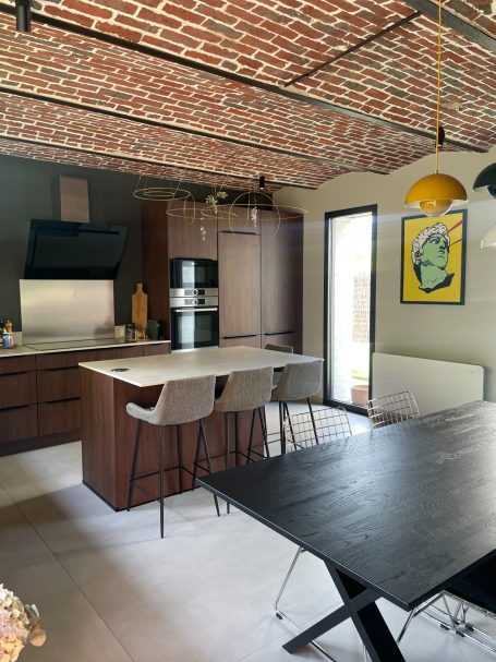 Cuisine moderne avec poutres en brique, meubles en bois et coin repas élégant.