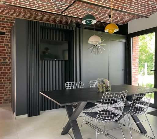 Cuisine moderne avec mur en briques, table à manger et éclairage suspendu coloré.